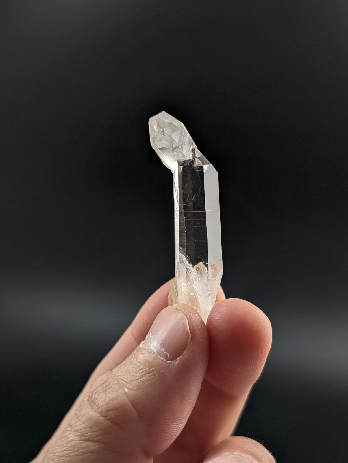 A clear, transparent quartz crystal with a pointed tip and faceted sides.