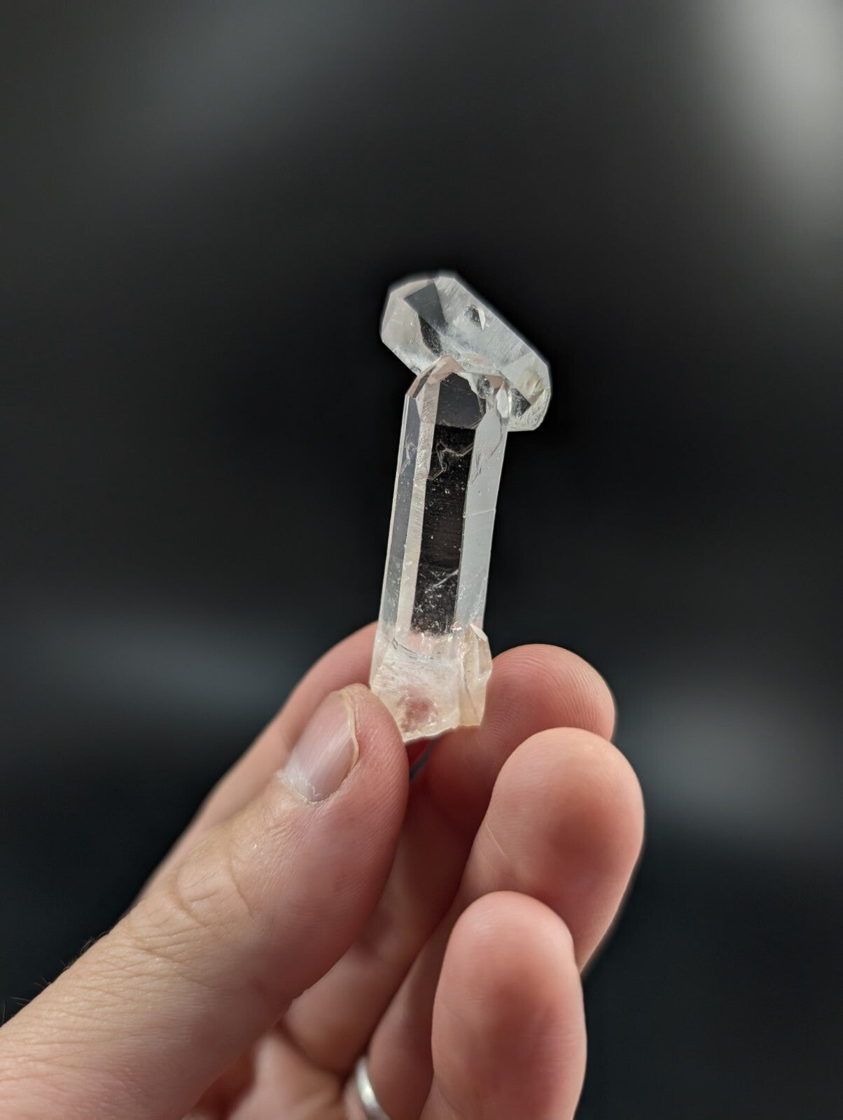 A clear, translucent quartz crystal with a faceted top and natural internal inclusions.