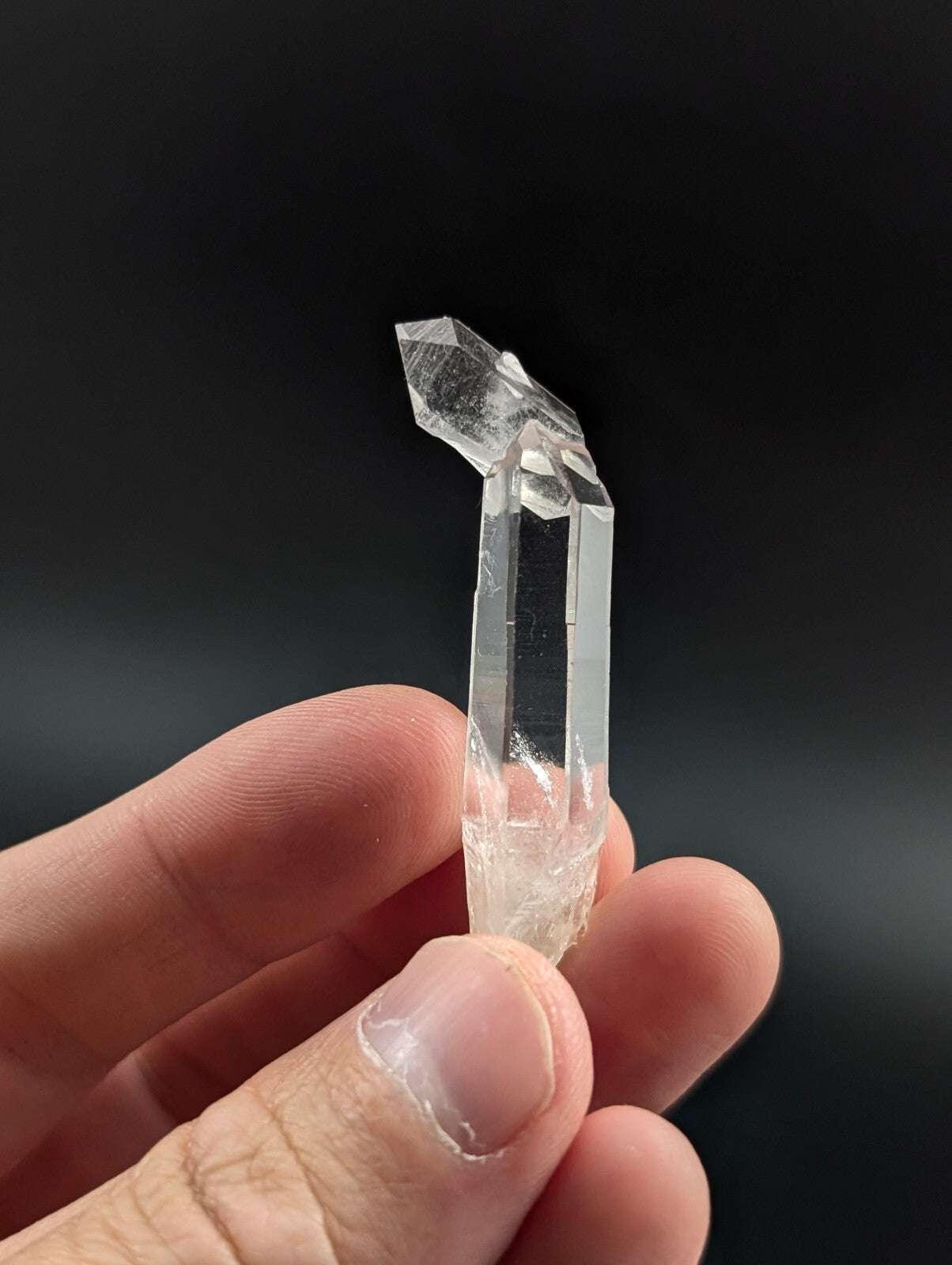 A clear, transparent quartz crystal with a pointed tip and faceted sides.