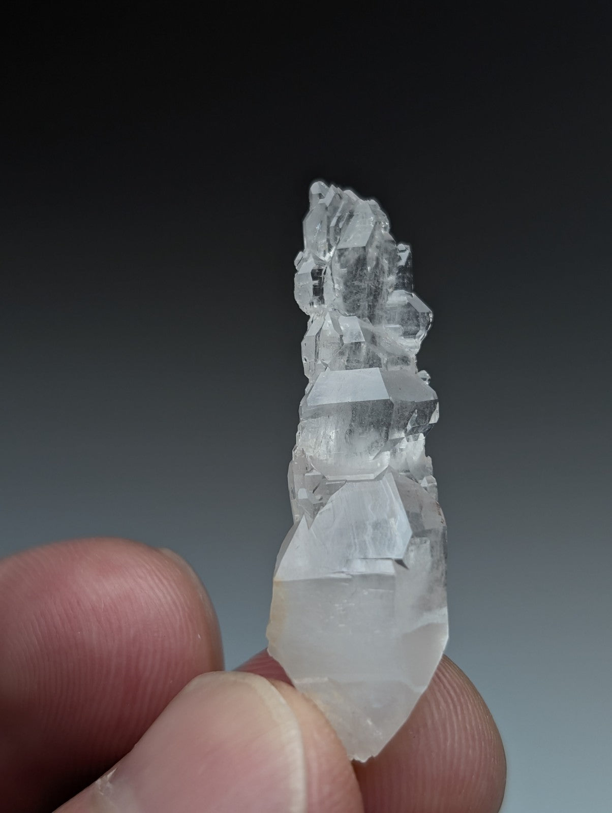 A translucent clear quartz crystal cluster with pointed tip and layered facets from garland county arkansas usa