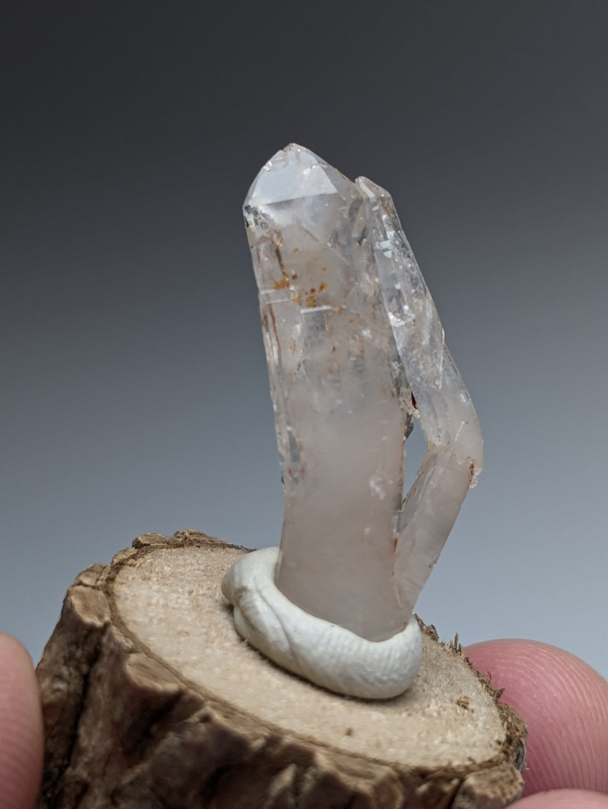 A clear quartz crystal cluster with translucent facets and natural inclusions on a wood base from garland county arkansas