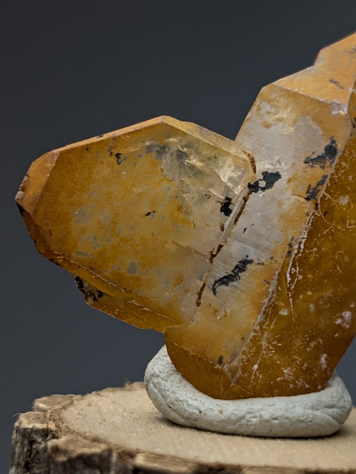 A translucent golden-yellow quartz crystal cluster with natural inclusions on a natural wood base from garland county