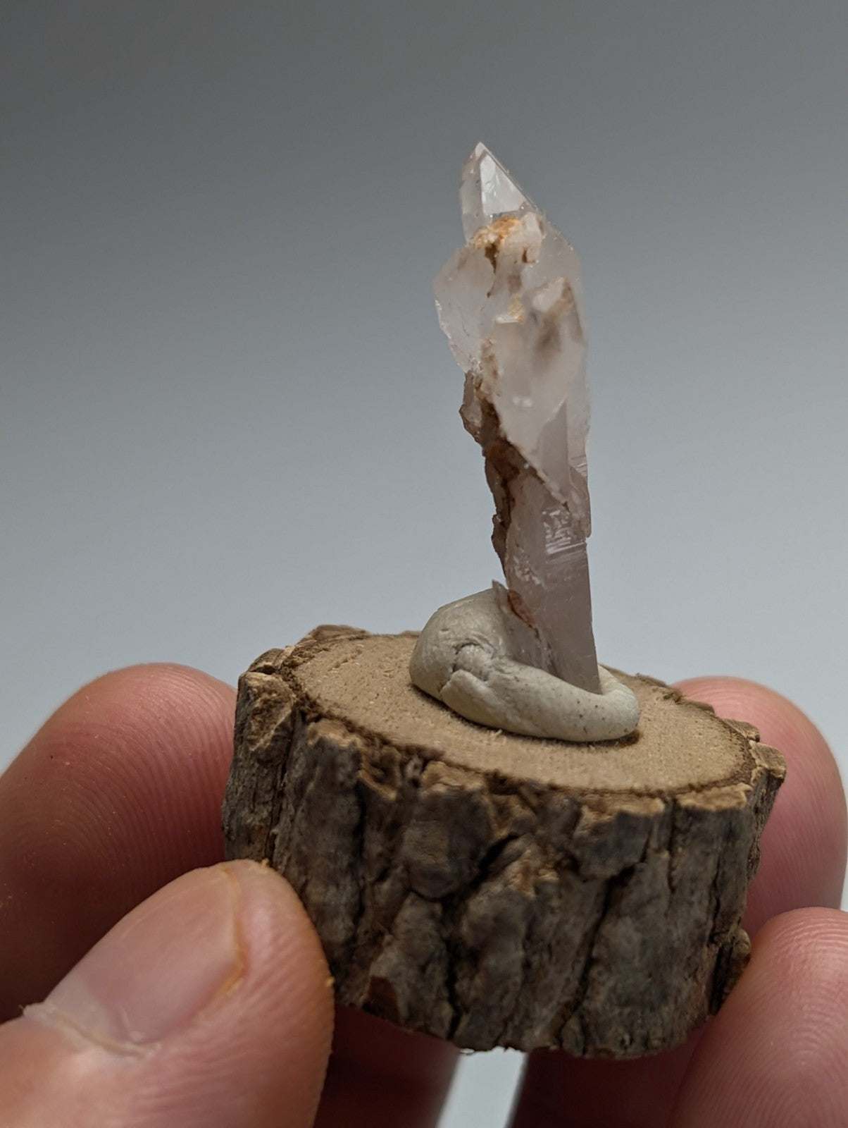 A translucent quartz crystal with natural inclusions on a rustic wooden base from montgomery county Arkansas
