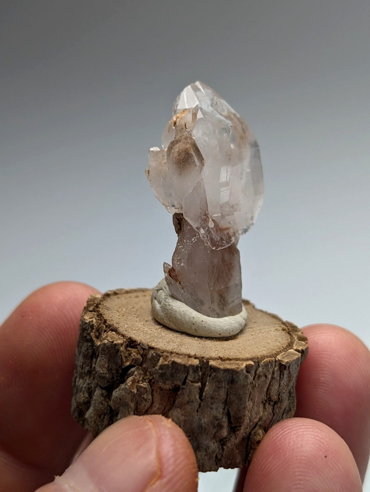 A clear quartz crystal cluster in white mounted on a rustic natural wood slice from montgomery county arkansas