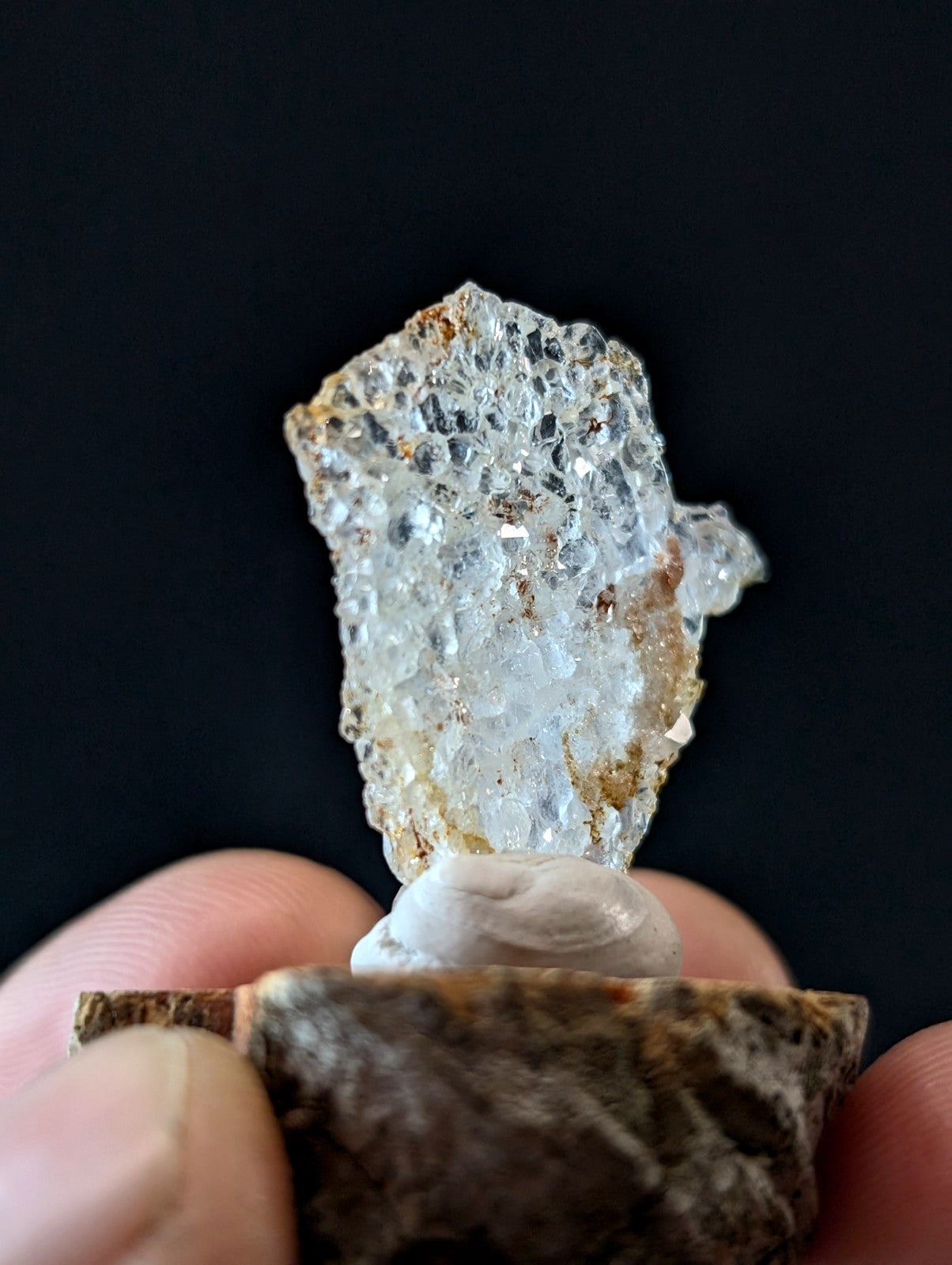 A translucent, crystalline mineral specimen with a honeycomb-like internal structure and patches of rust-colored matrix.