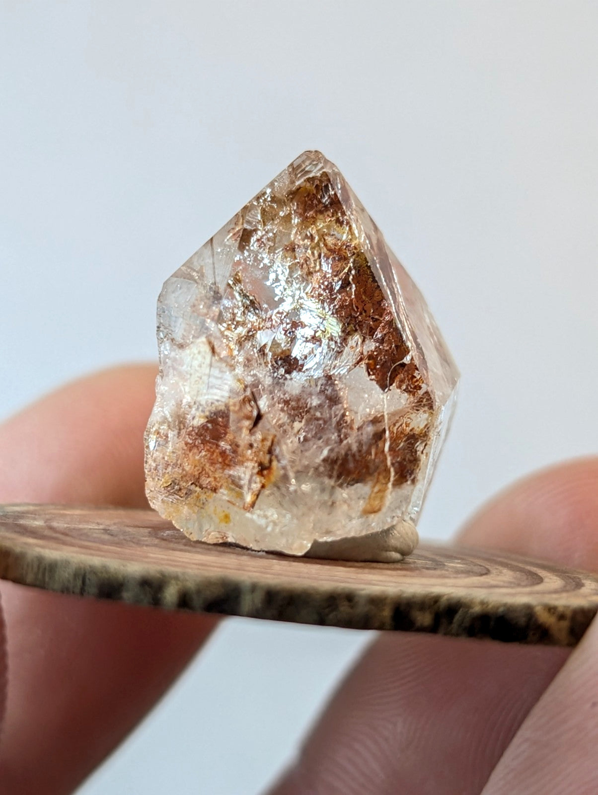 A translucent, faceted crystal with golden-brown inclusions and a natural, rough-edged form.