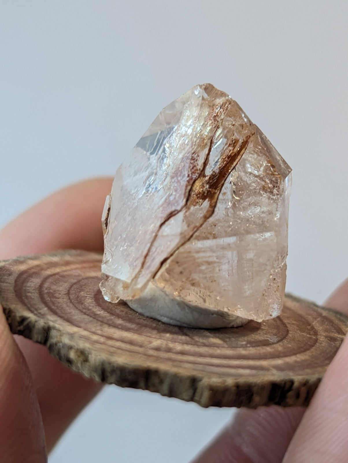 A translucent, faceted quartz crystal with natural brown inclusions and a rough-edged, pointed top.