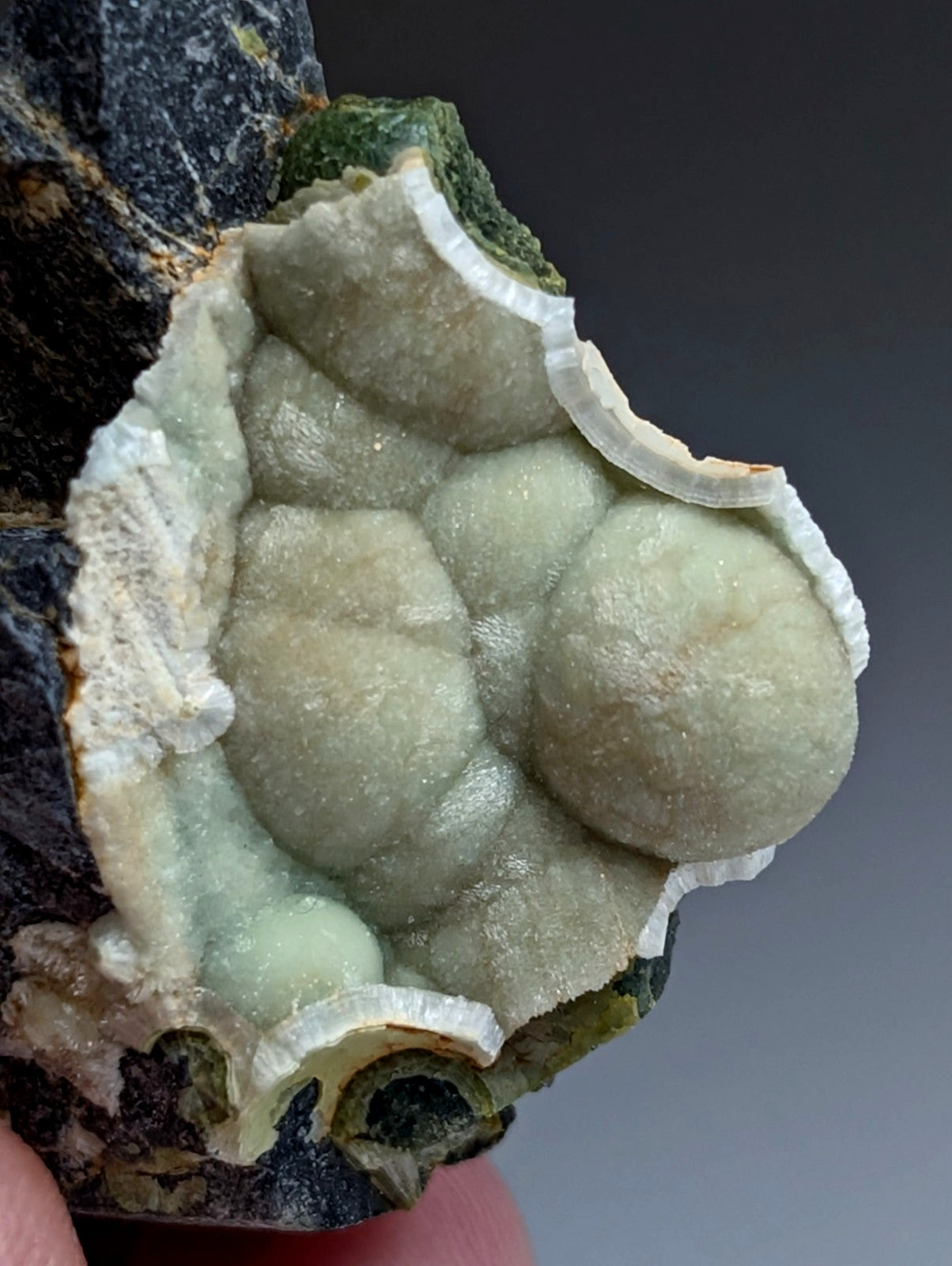 A pale green translucent wavellite mineral with bubble-like formations and white crystalline rim from mauldin mountain Arkansas