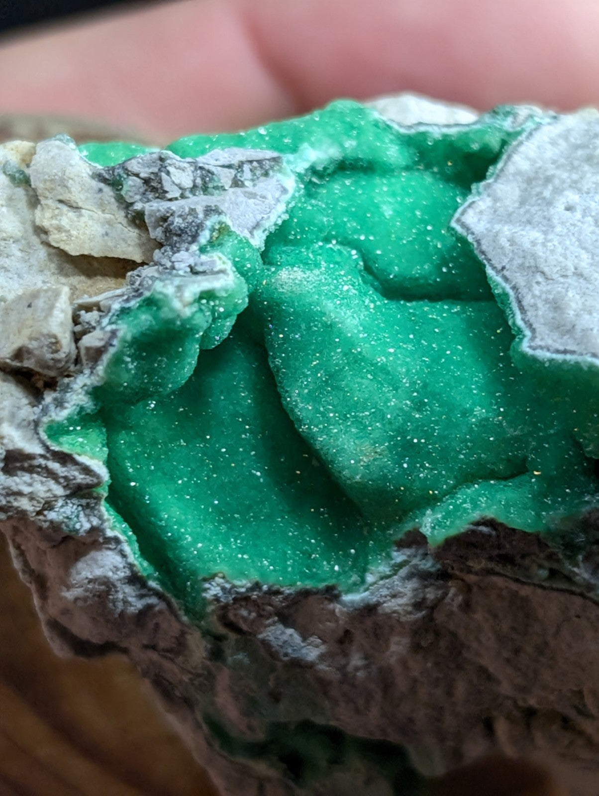 Vibrant emerald-green mineral specimen with sparkling crystalline texture and grayish rock matrix.
