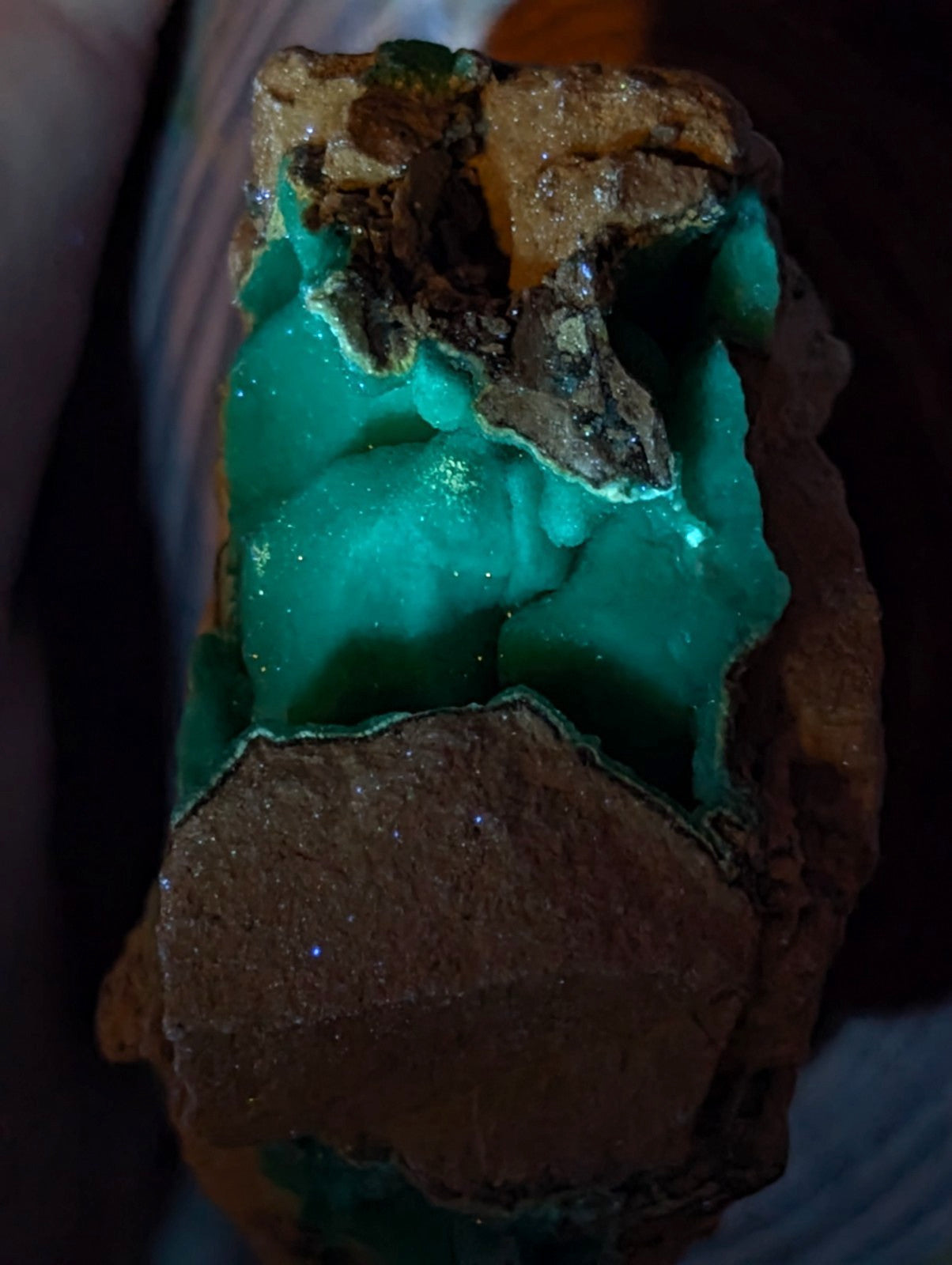 Vibrant emerald-green malachite mineral specimen with a rough, earthy brown matrix and glittering crystalline formations.