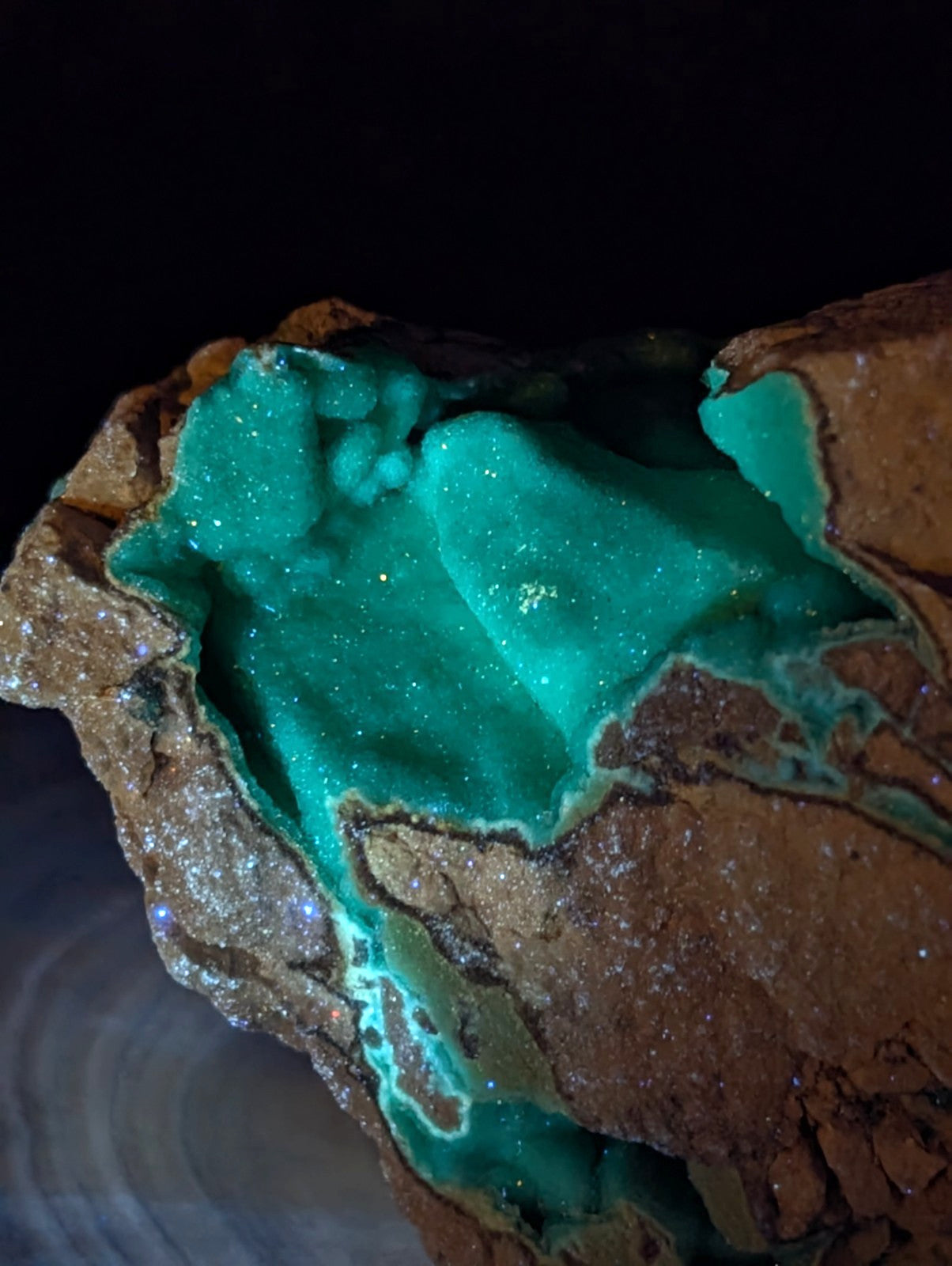 Vibrant emerald-green malachite crystal formation nestled within a rugged, earthy brown rock matrix.