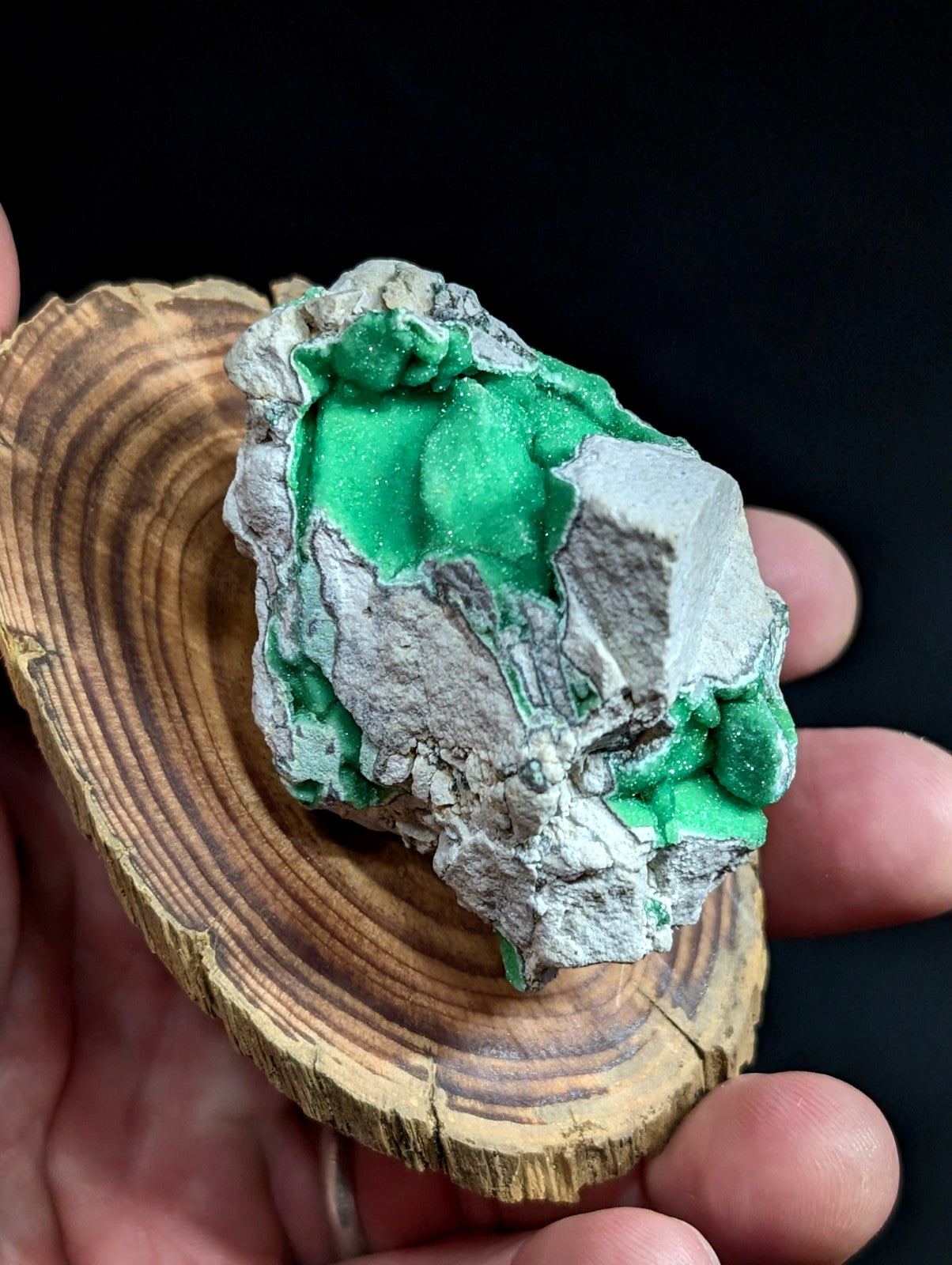 A vibrant green malachite mineral specimen with a rough, crystalline texture set against a contrasting gray matrix.