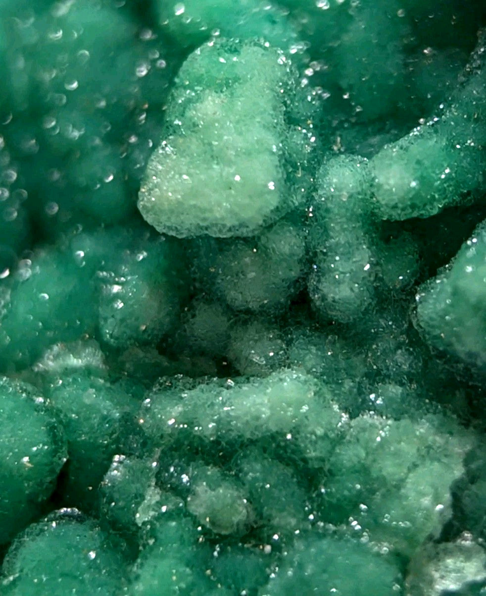 Vibrant green, crystalline mineral formations with a sparkling, textured surface.