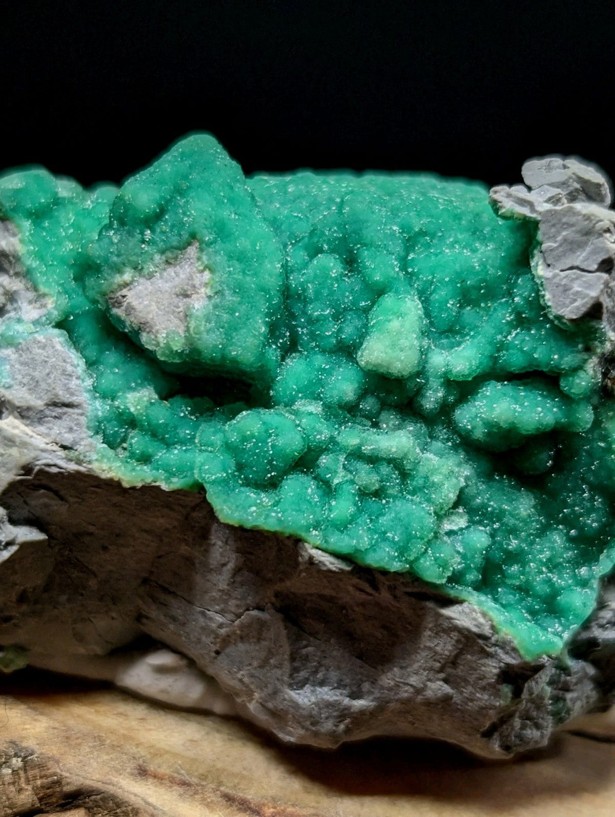 Vibrant emerald-green malachite mineral specimen with a crystalline, textured surface set against gray rock matrix.