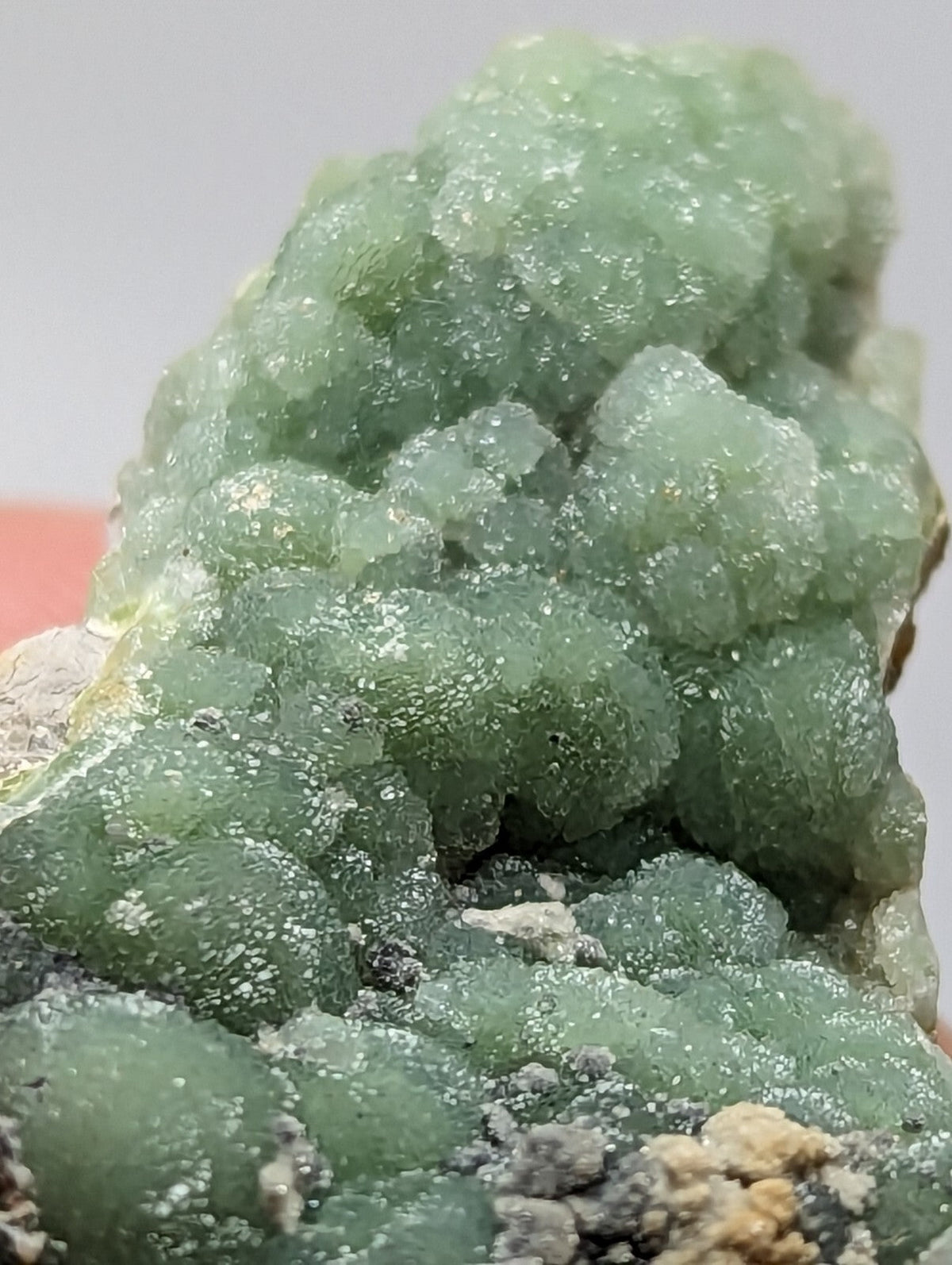 A cluster of translucent green crystals with a bumpy, textured surface.