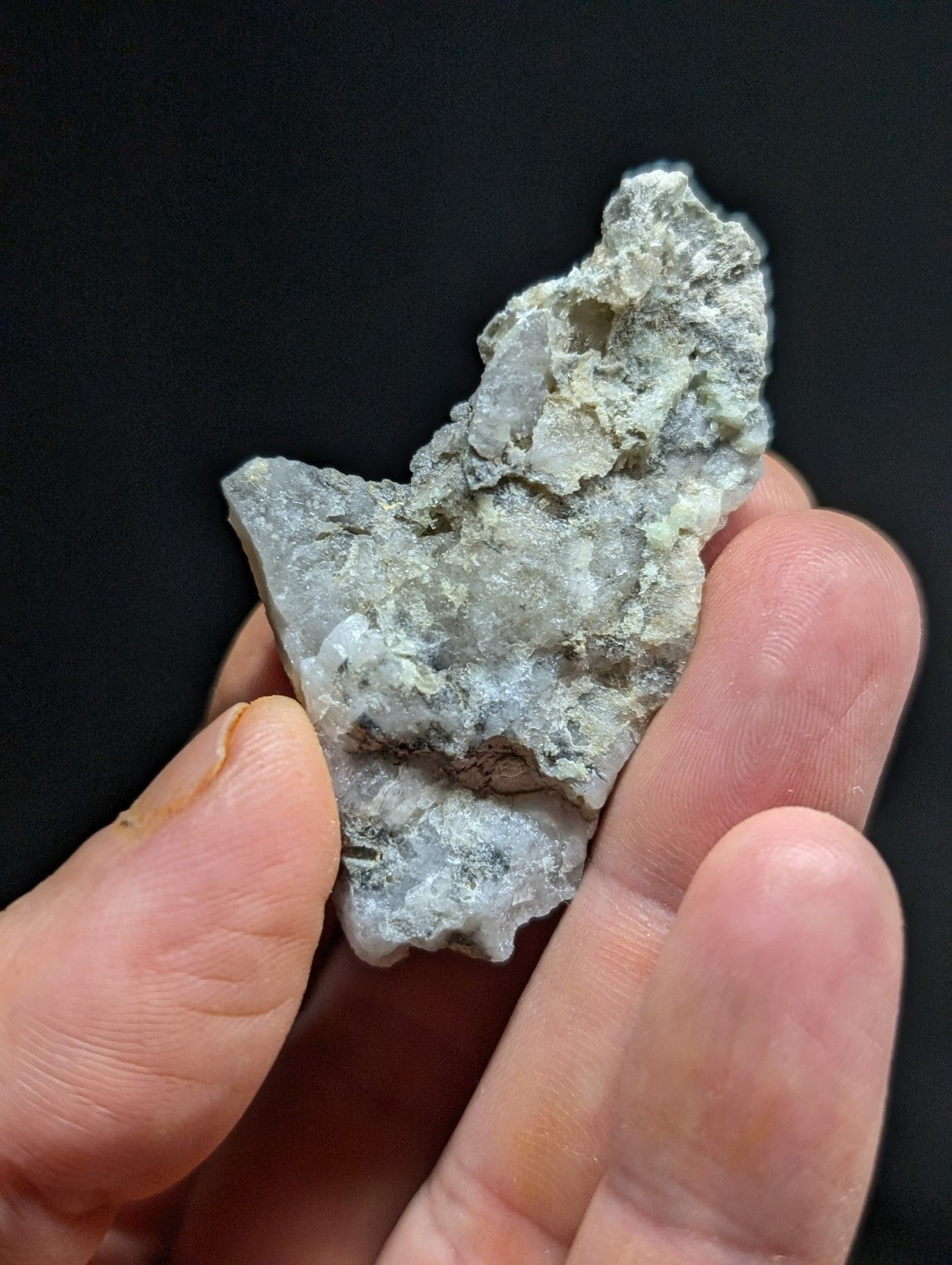 A rough, irregularly shaped gray rock with a textured surface held in someone’s hand.