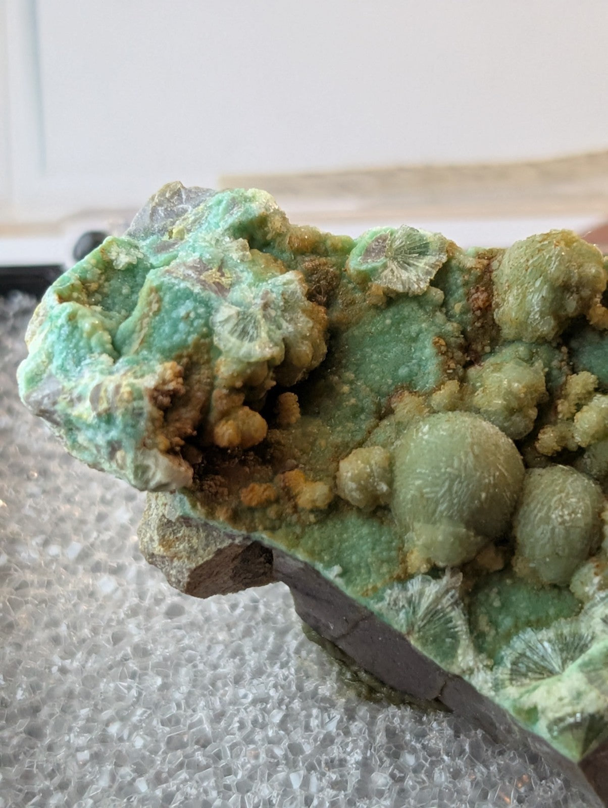 A vibrant green mineral specimen featuring intricate, rounded formations with a textured surface and subtle brownish accents.