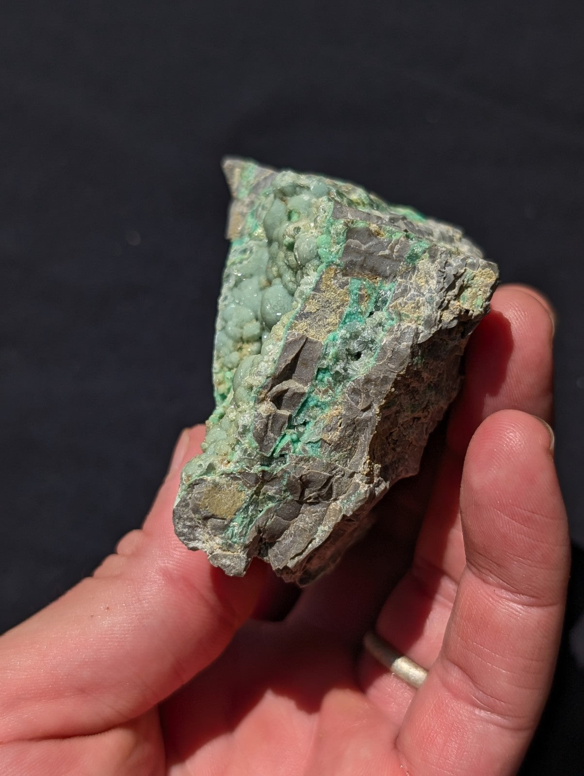 A rough, irregularly shaped mineral specimen with a mottled green and gray surface.
