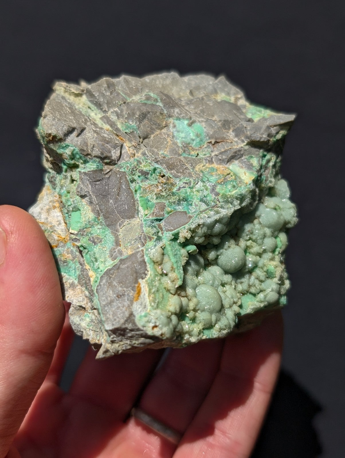 A rough, irregularly shaped mineral specimen with a gray matrix and vibrant green veining and rounded nodules.