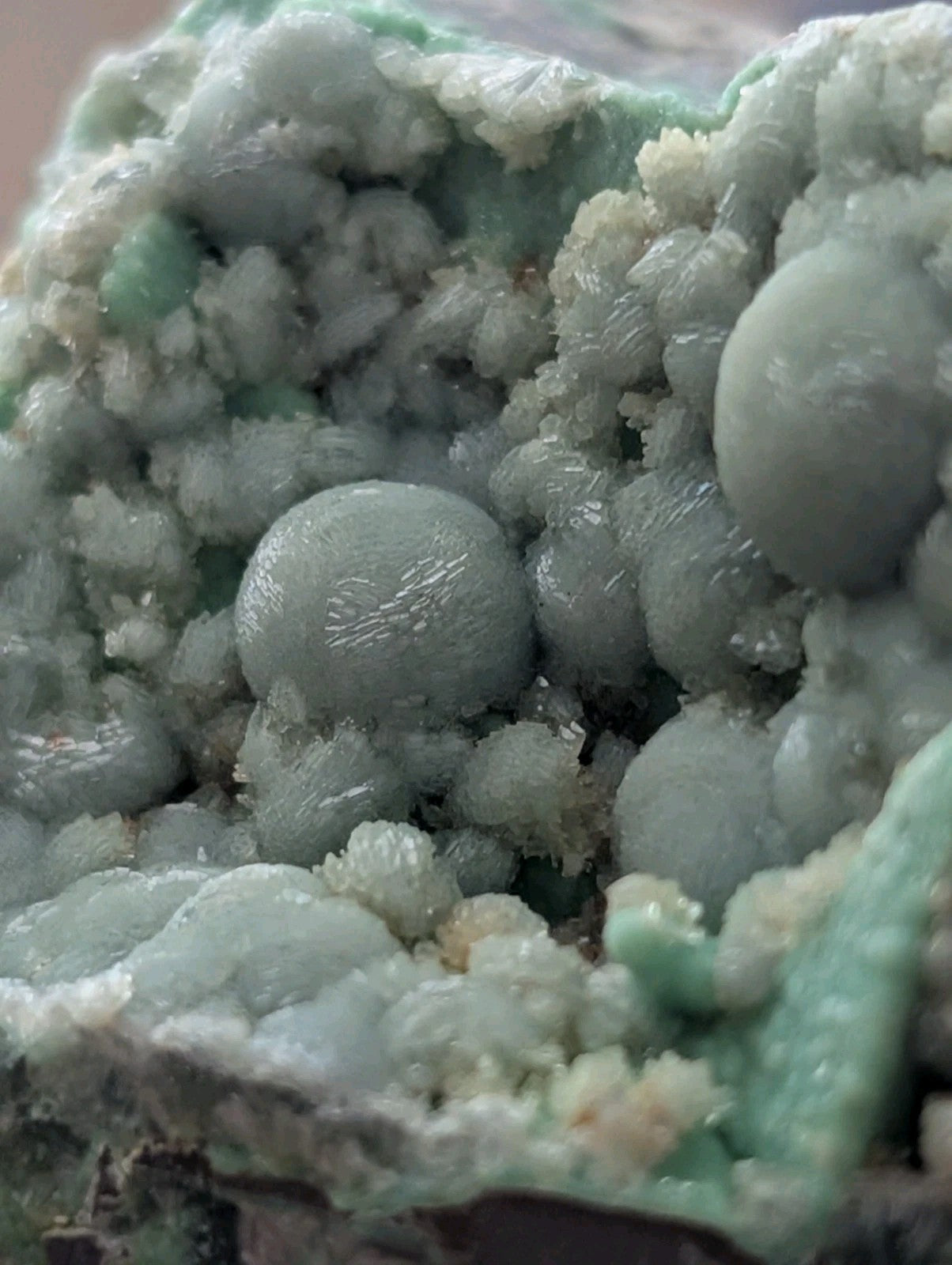 A cluster of pale green, rounded mineral formations with a crystalline texture.