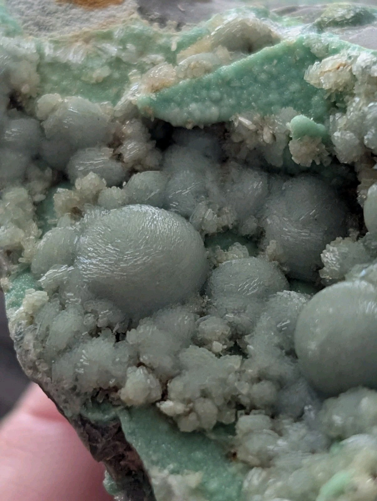 A cluster of translucent, pale green spherical crystals with a rough, crystalline matrix.
