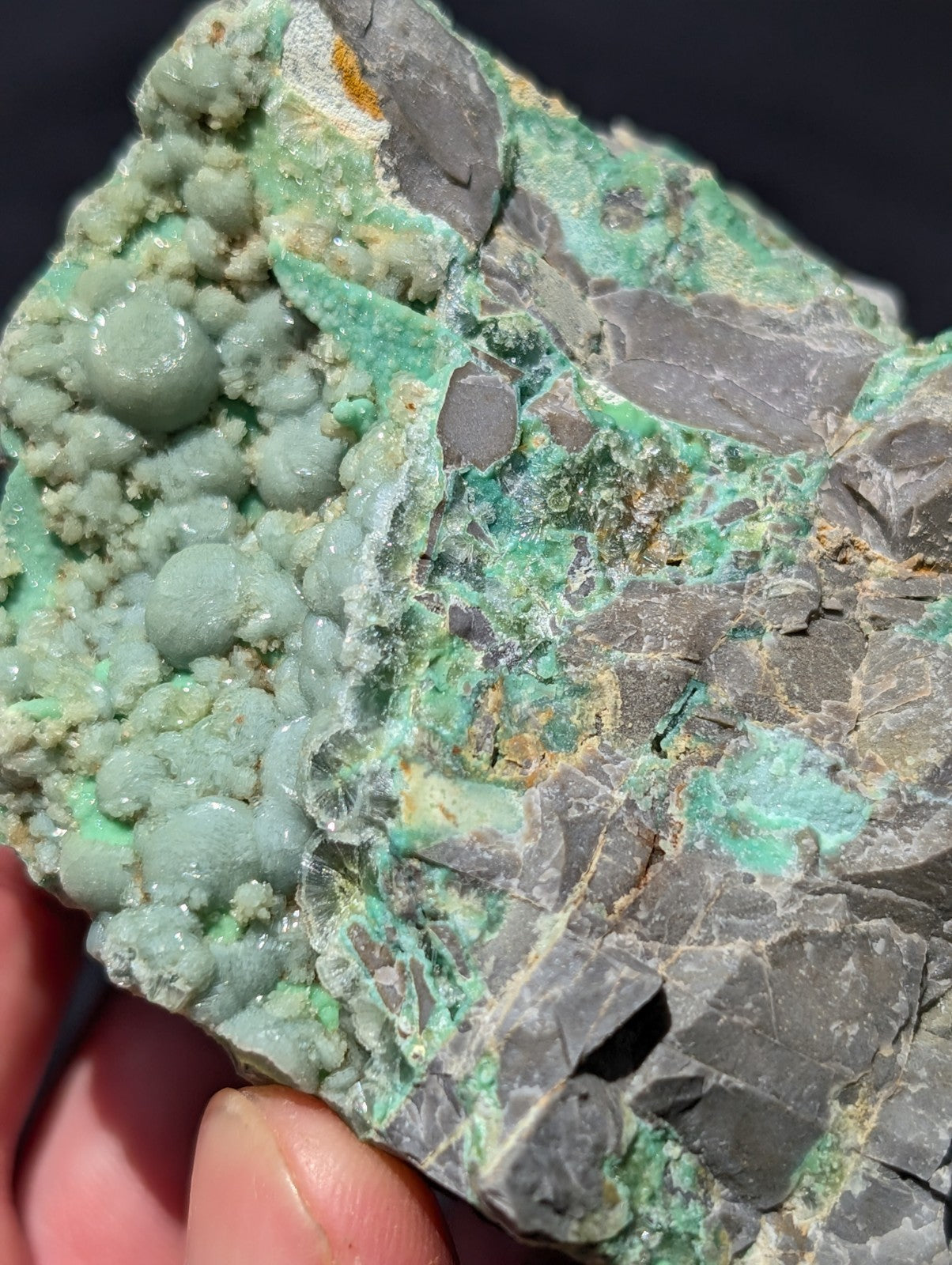 A textured, irregularly shaped mineral specimen featuring vibrant green crystalline formations over a grayish matrix.