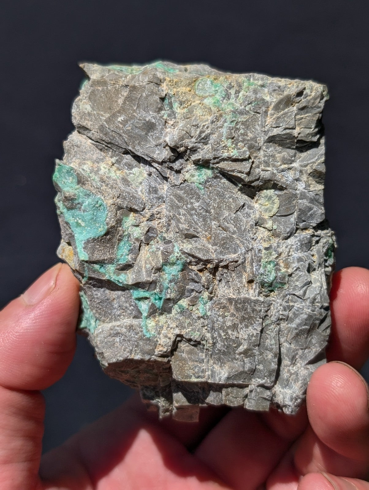 A rough, irregularly shaped piece of mineral with a grayish base and patches of vibrant turquoise patina.