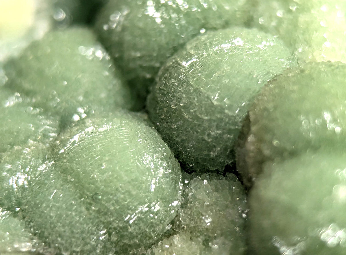 Translucent green crystalline formations with a glossy, textured surface