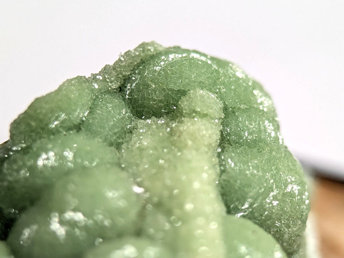 A translucent green, crystalline mineral specimen with a rough, bubbly texture and glistening surface.