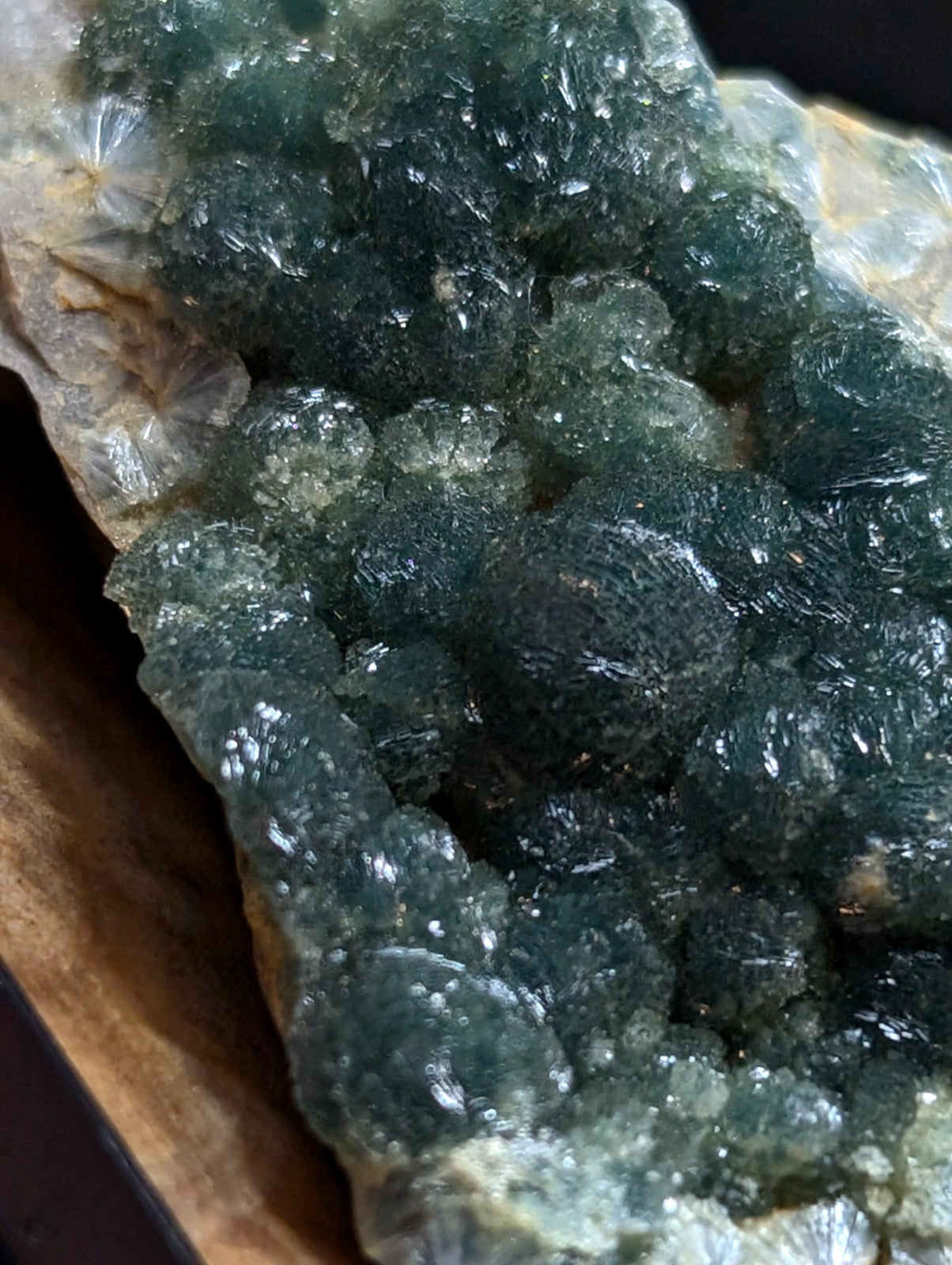 A cluster of deep green, translucent fluorite crystals with a glossy surface and intricate crystalline formations.