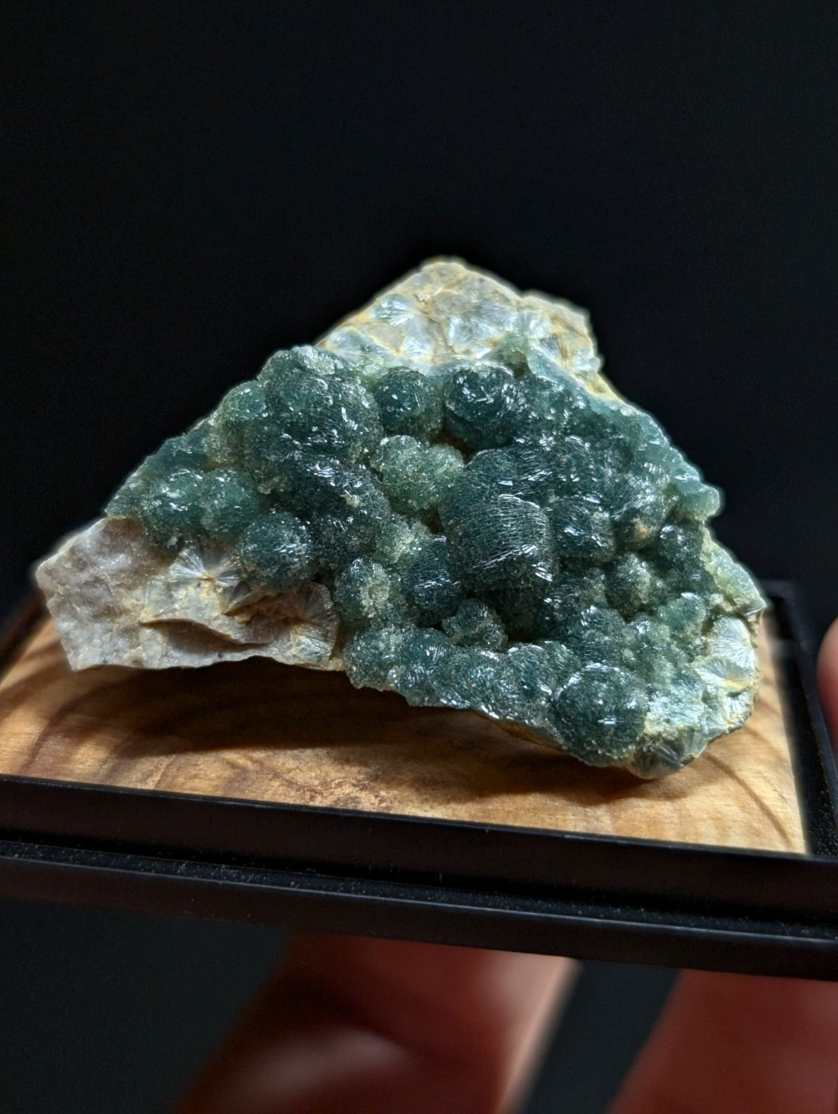 A cluster of translucent green fluorite crystals growing from a light-colored rock matrix.