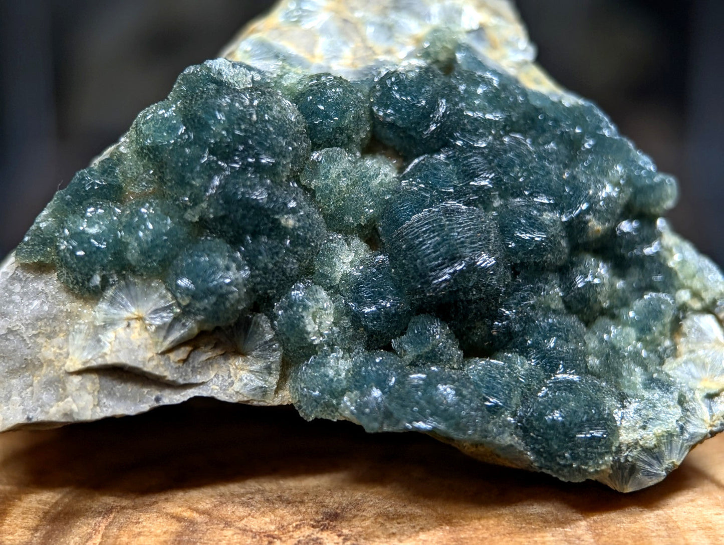 A cluster of deep teal, translucent fluorite crystals growing from a rough, light gray rock matrix.