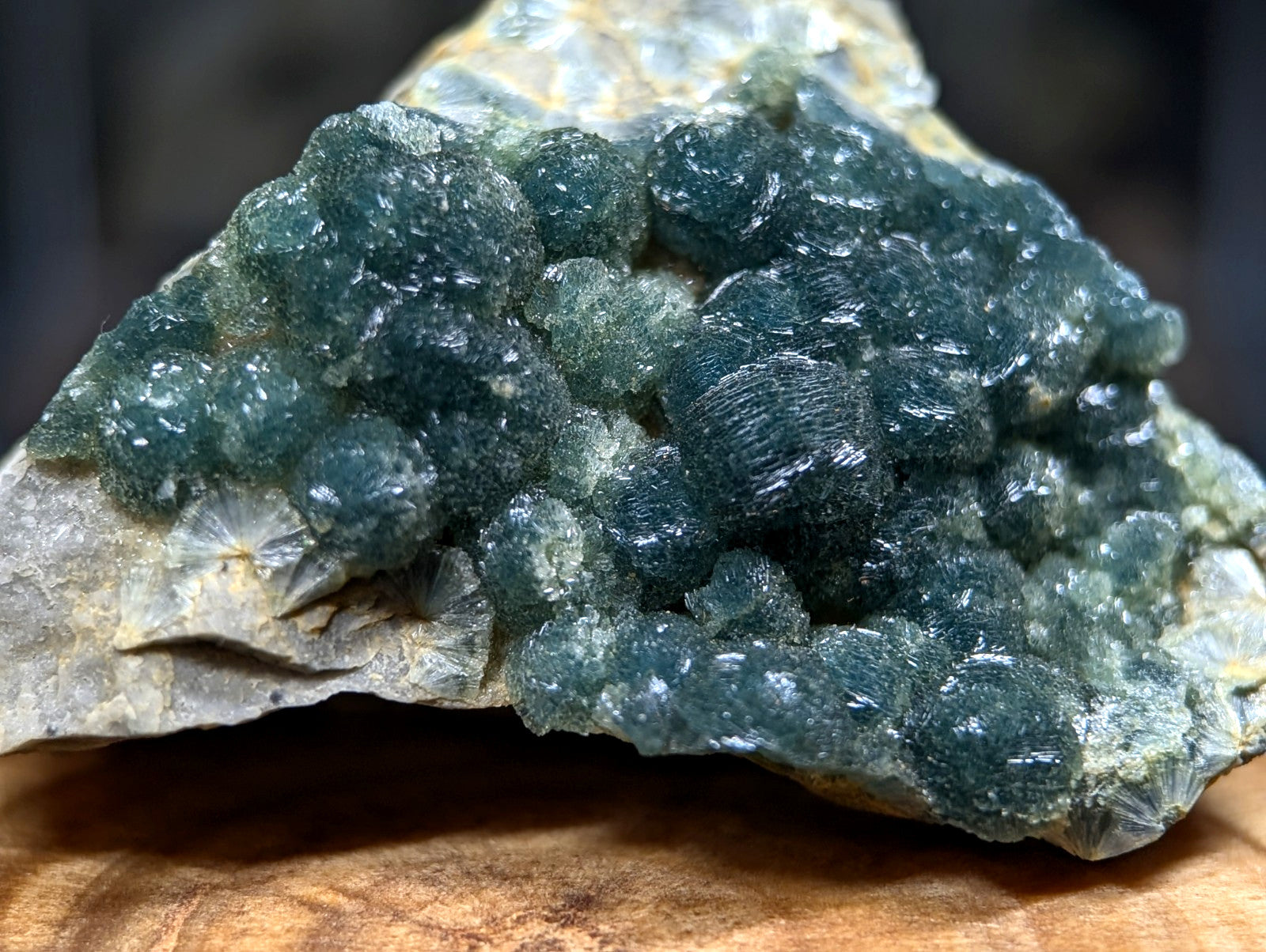 A cluster of deep teal, translucent fluorite crystals growing from a rough, light gray rock matrix.