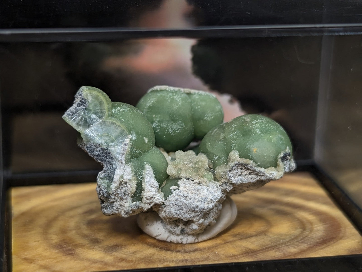 A green, translucent mineral specimen with rounded, bulbous formations and a crystalline base.