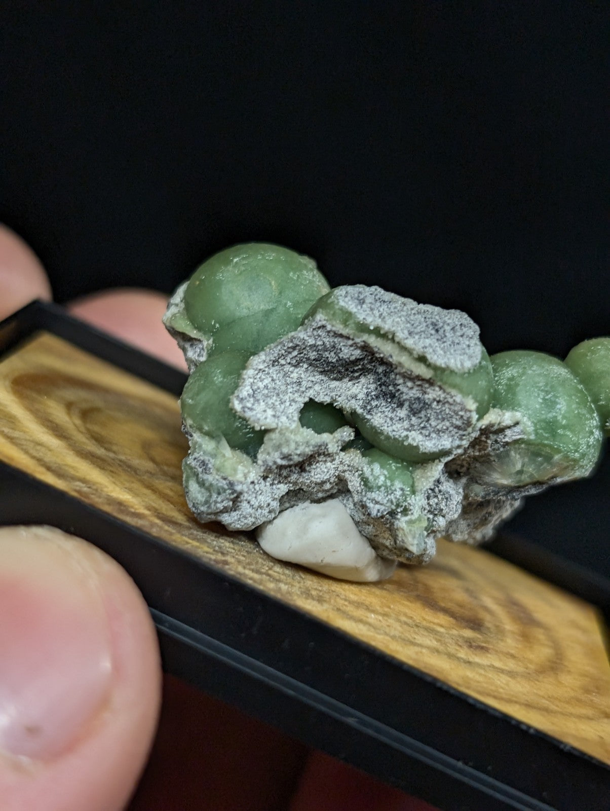 A green, translucent jade-like mineral specimen with a rough, textured surface and embedded white quartz crystals.