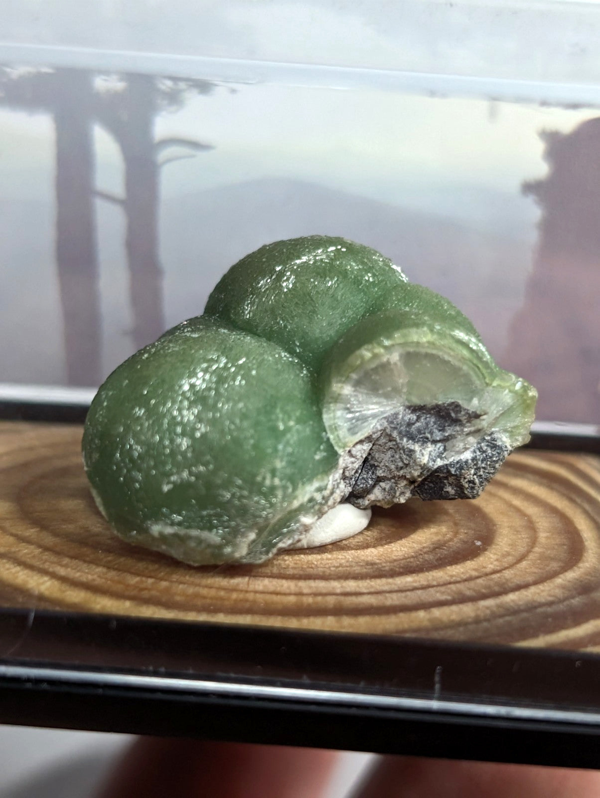 A translucent green gemstone with a smooth, rounded surface and subtle white speckles.