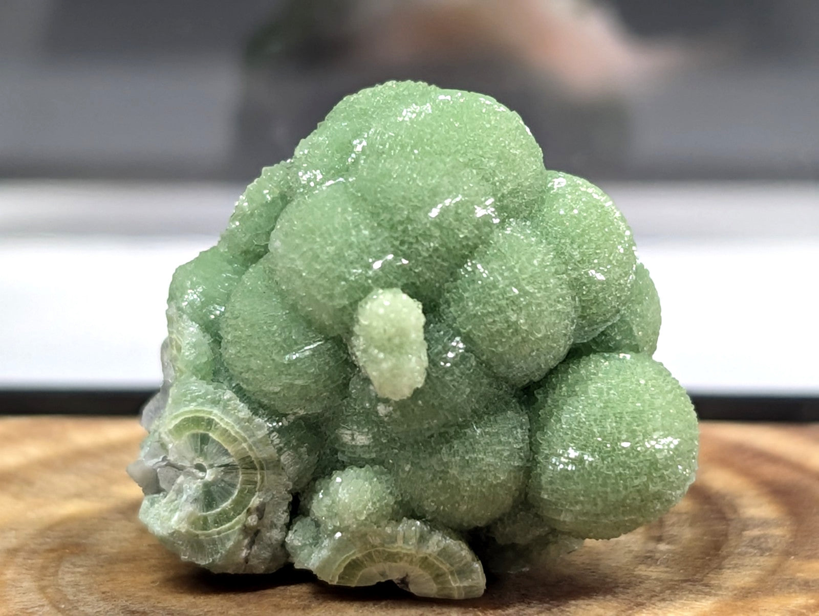 A vibrant green, spherical crystal cluster with a glossy, textured surface and subtle translucency.