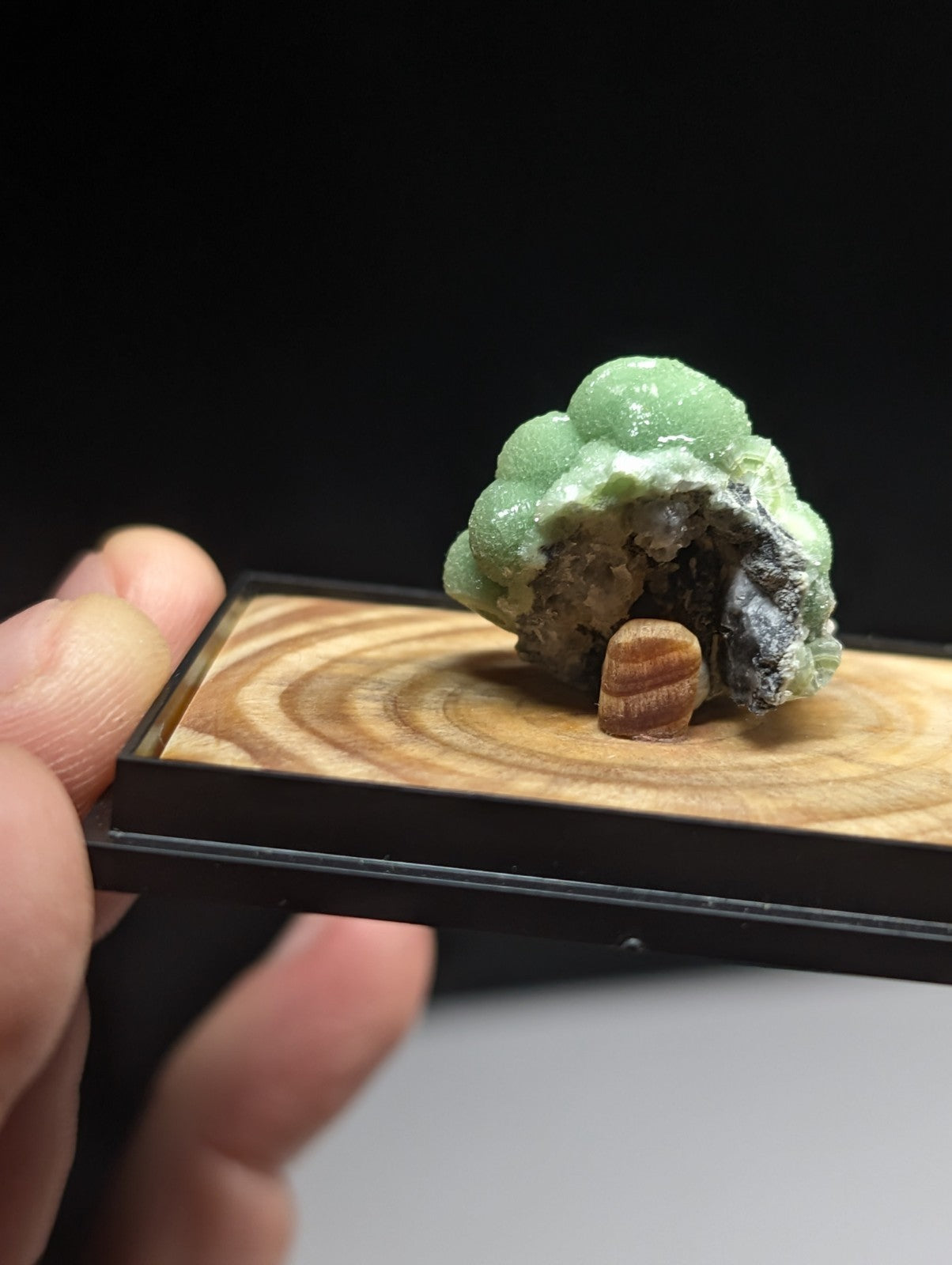 A vibrant green, bumpy mineral specimen with a textured surface and dark gray base.