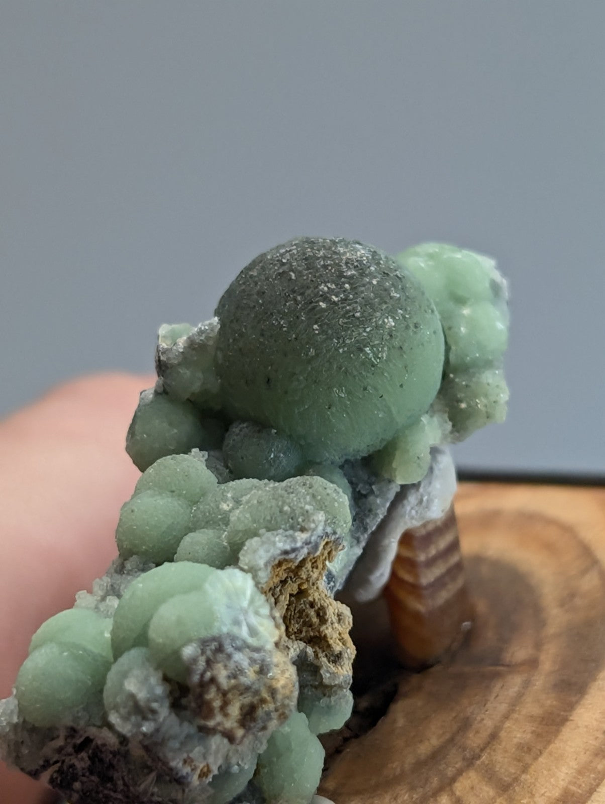 A green, spherical mineral specimen with a textured surface and clustered formations.