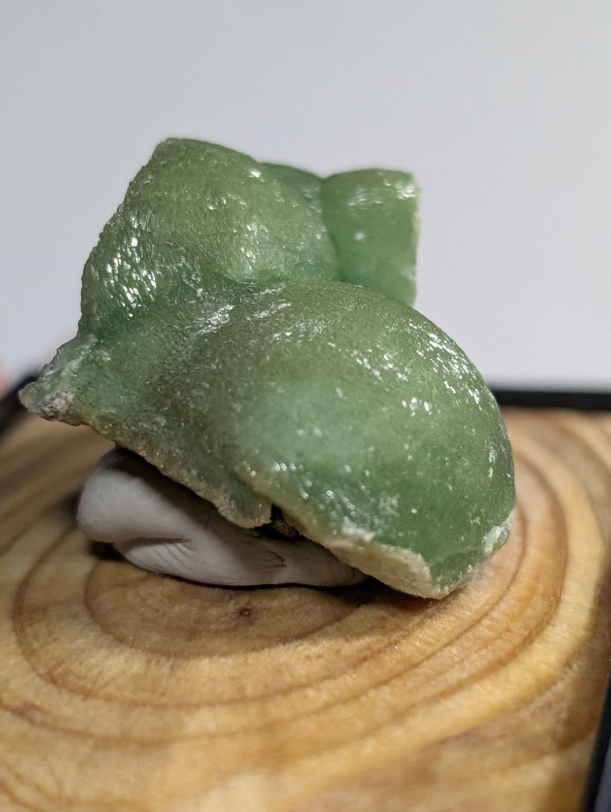 A translucent green, glossy resin figurine of a seated frog with smooth, slightly textured surfaces.