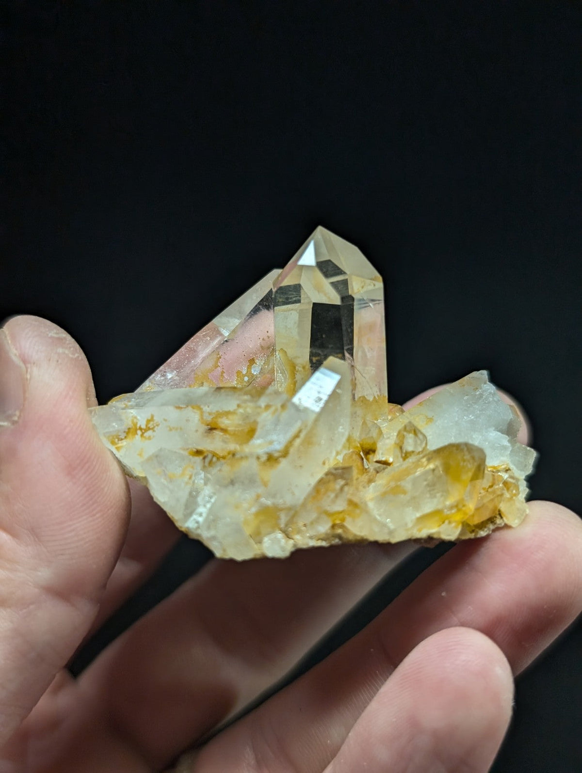 A translucent, pale yellow quartz crystal cluster with golden inclusions and sharp geometric facets.