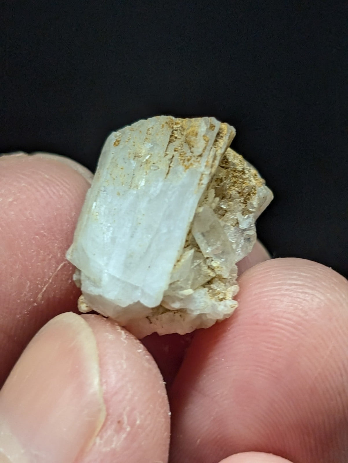 A translucent white mineral specimen with visible crystalline facets and a rough, earthy matrix.