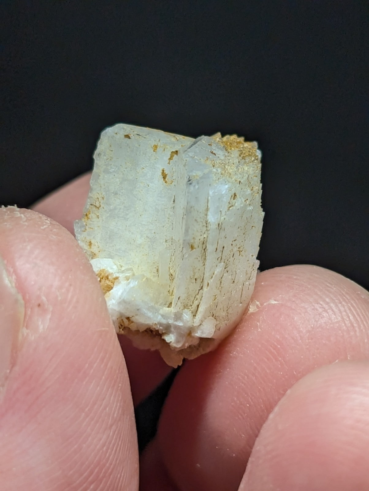 A translucent white quartz crystal with golden mineral inclusions and a rough, naturally fractured surface.