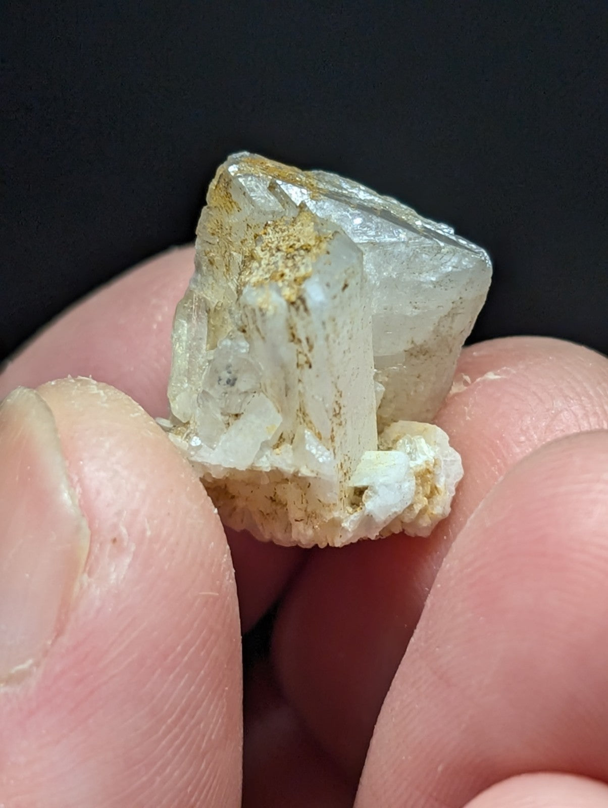 A translucent, pale quartz crystal cluster with golden mineral inclusions and a rough, natural base.