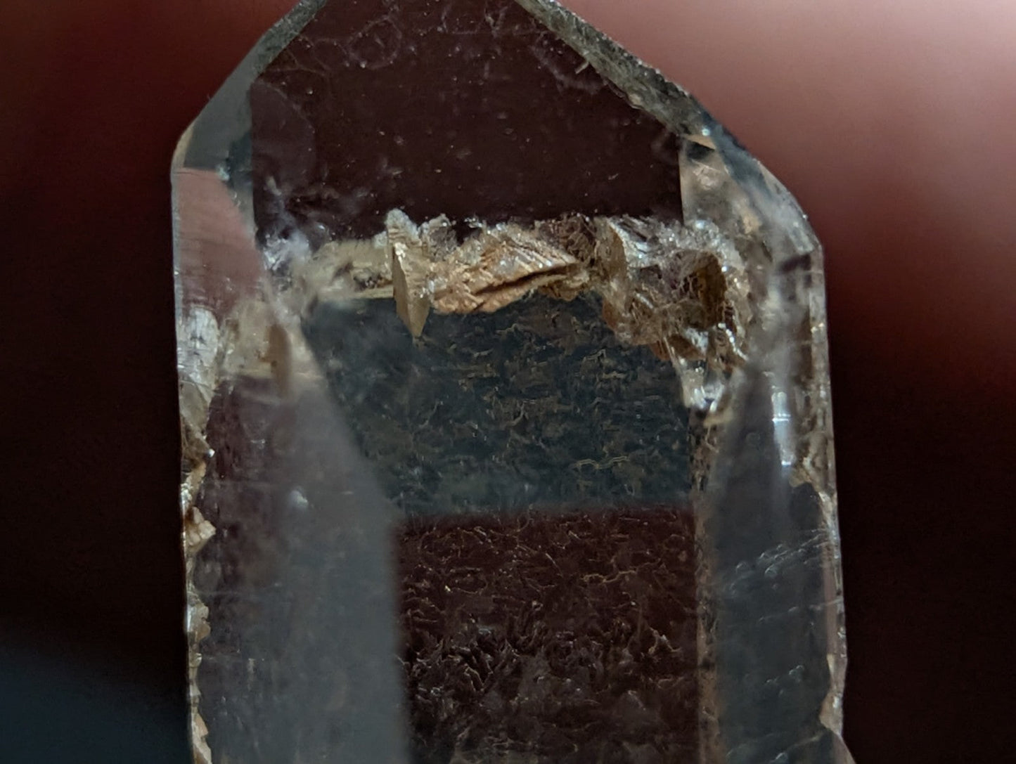A translucent, clear quartz crystal with a pointed top and visible internal inclusions.