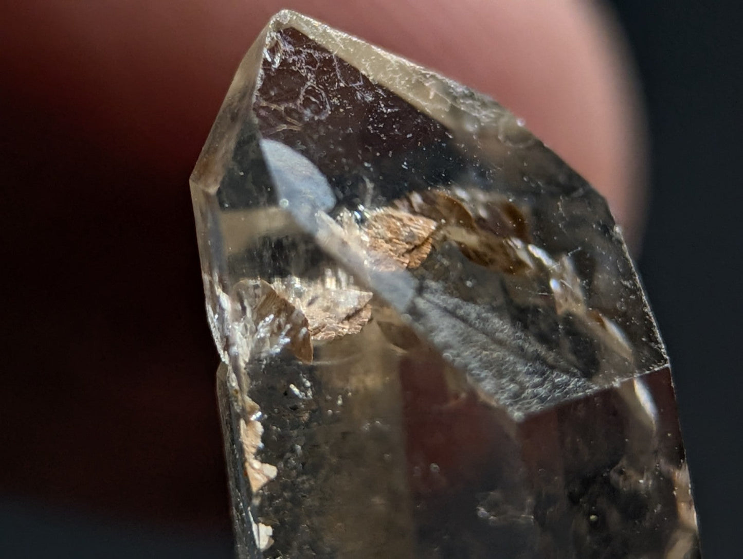 A translucent smoky quartz crystal with natural inclusions and a pointed, faceted top.
