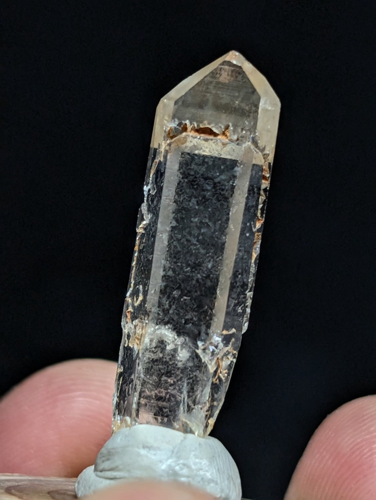 A translucent, clear quartz crystal with a pointed tip and visible internal inclusions.