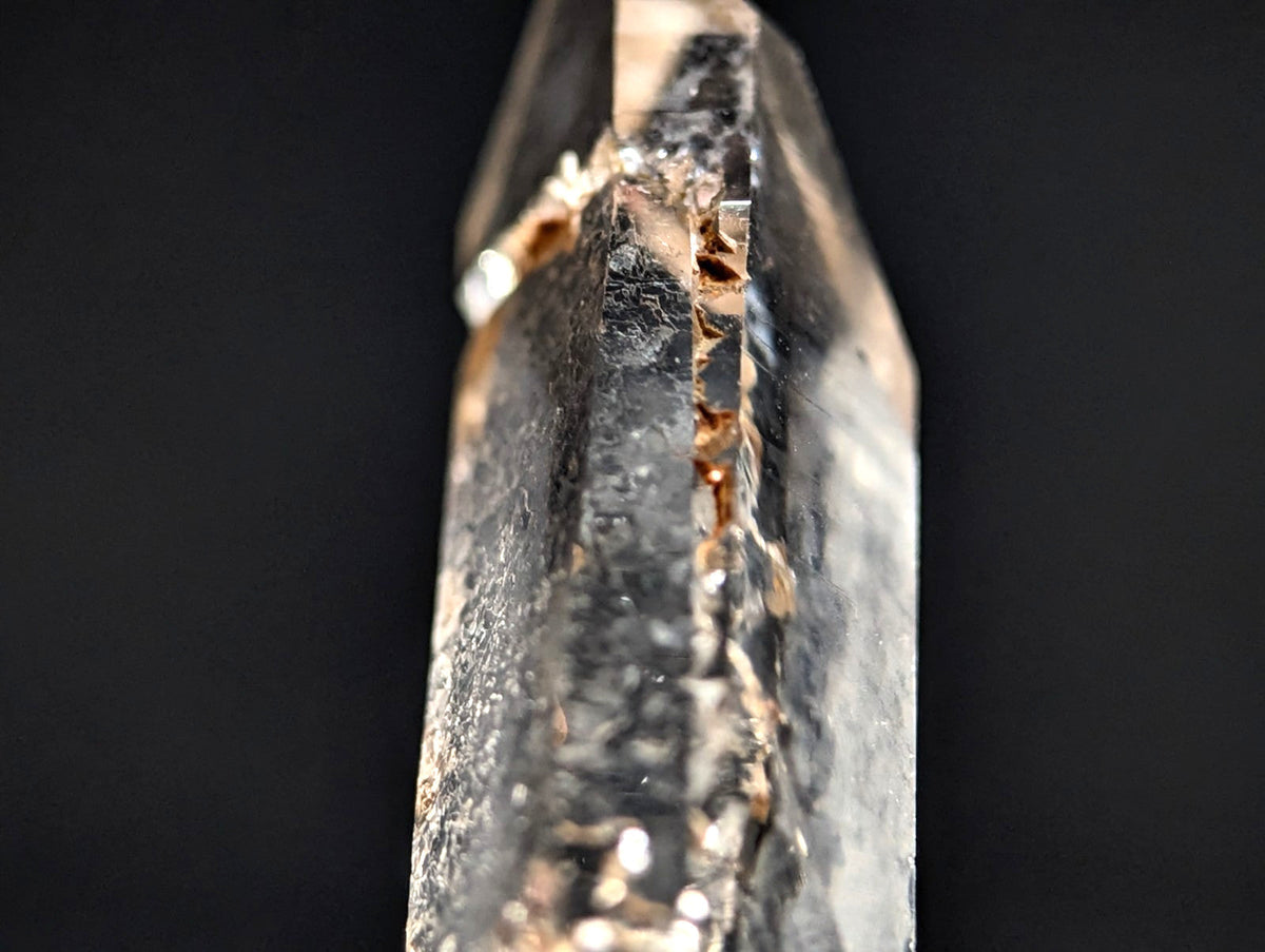 A translucent, clear quartz crystal with a pointed tip and visible internal inclusions.