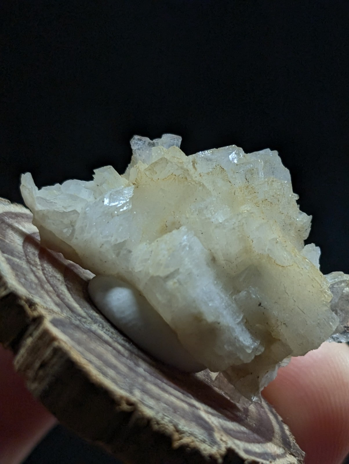 A translucent, crystalline mineral specimen with a pale white and slightly yellowish hue, featuring jagged edges and natural growth patterns.