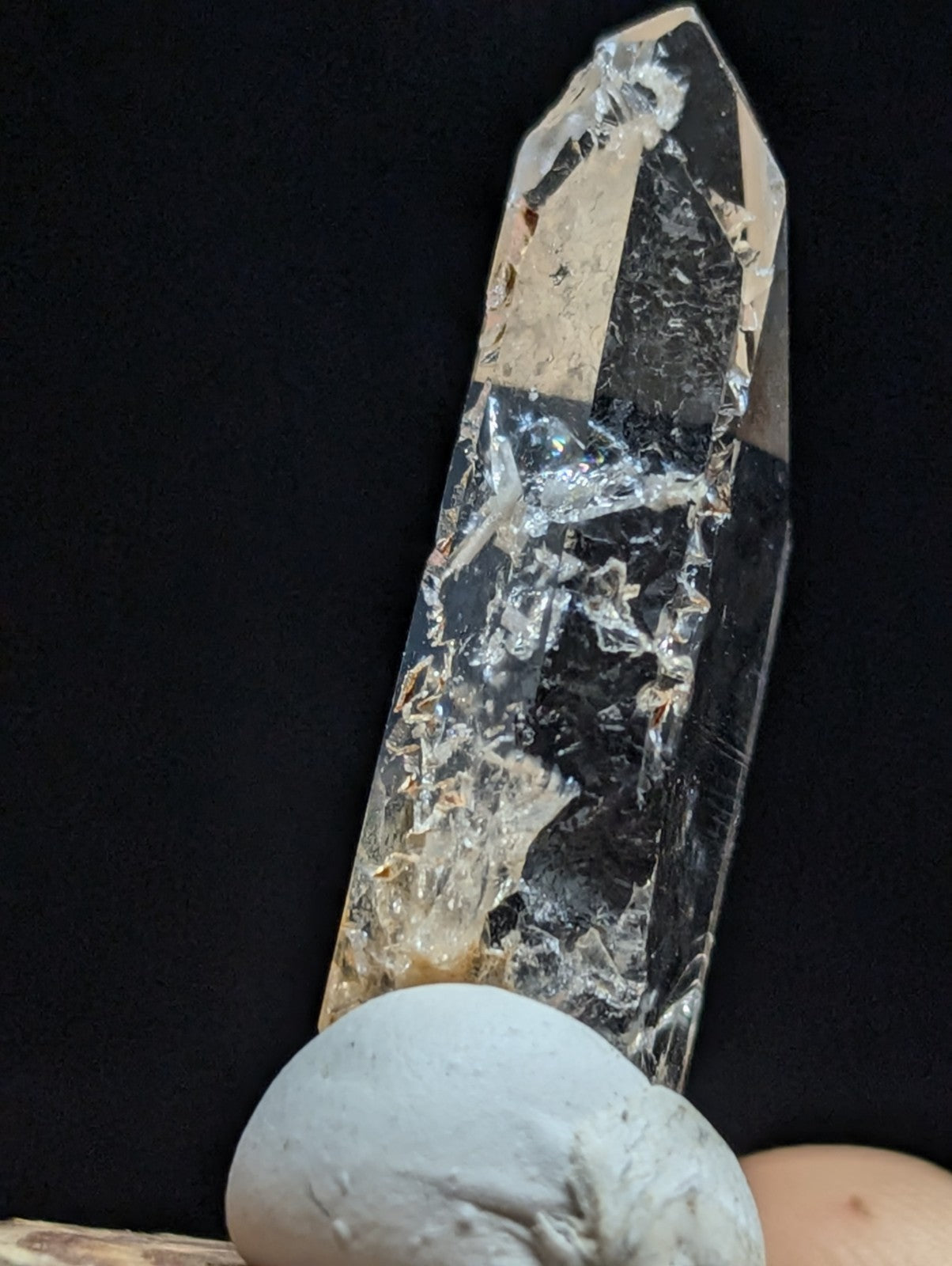 A clear, faceted quartz crystal with natural inclusions and a pointed tip.